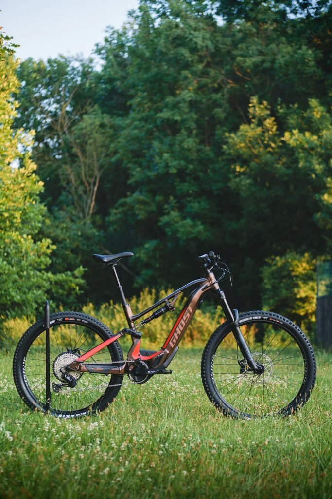 Electric mountain bike parked on a grassy field with a forest backdrop.