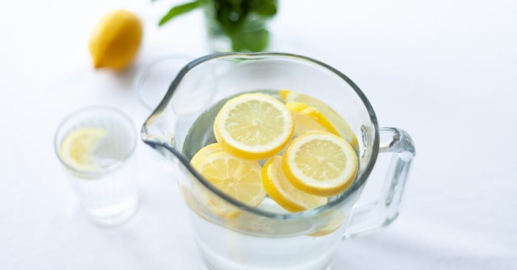 Top-down view of lemon slices in a glass pitcher filled with water, offering a refreshing drink option.